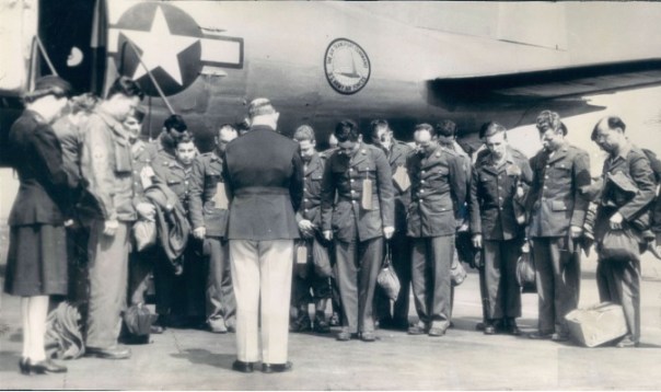“The first group of soldiers to return to the United States after news of the surrender of Germany, bow their heads in prayers offered by Capt. Edward J. Barber, Chaplain at the air transport command base at La Guardia field. All of the men were wounded in European campaigns. (AP Wirephoto from Air Transport Command).”
