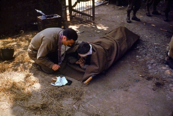 An-American-Army-chaplain-kneels-next-to-a-wounded-soldier-in-order-to-administer-the-Eucharist-and-Last-Rites-France-1944