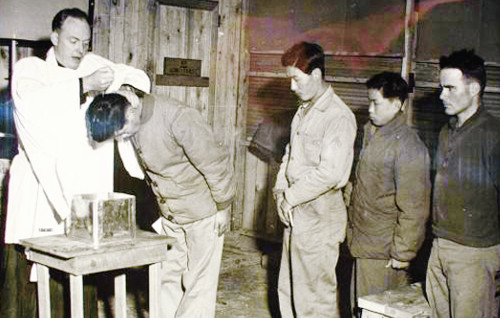 U.S. Navy chaplain Alexander Boyer baptizes a Korean worker employed at his base, in the winter of 1952.